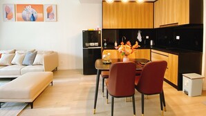 A modern kitchen with wooden cabinets, a black refrigerator, and a dining area with red chairs.