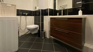A modern bathroom with a white toilet, a wooden vanity, a shower, and a radiator. - HomeApatr Dzerzhinsky Ave (Minsk)