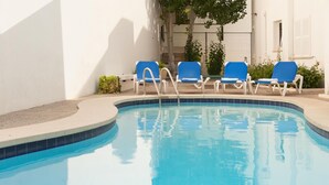 Ein Schwimmbad mit blauen Stühlen und einer gefliesten Kante.