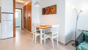 Eine kleine Küche mit Esstisch, Stühlen, einem Kühlschrank und einer Stehlampe.