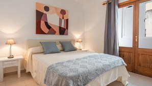 Ein Schlafzimmer mit einem Bett, zwei Nachttischen, einem Wandbild und einer Holztür.