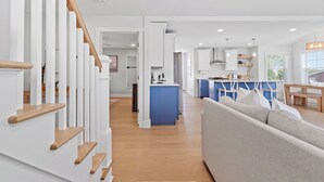 A modern kitchen with a blue island, wooden staircase, and a living area with a grey sofa. - Ideally located, game room, finished basement, fenced yard, lawn games, coffee (Middletown)