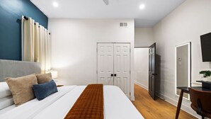 A modern hotel room with a large bed, a desk, a chair, and a TV. - ★HostWise Stays★ Stylish War Streets Retreat | Easy Walk to Stadiums & Dining (Pittsburgh)