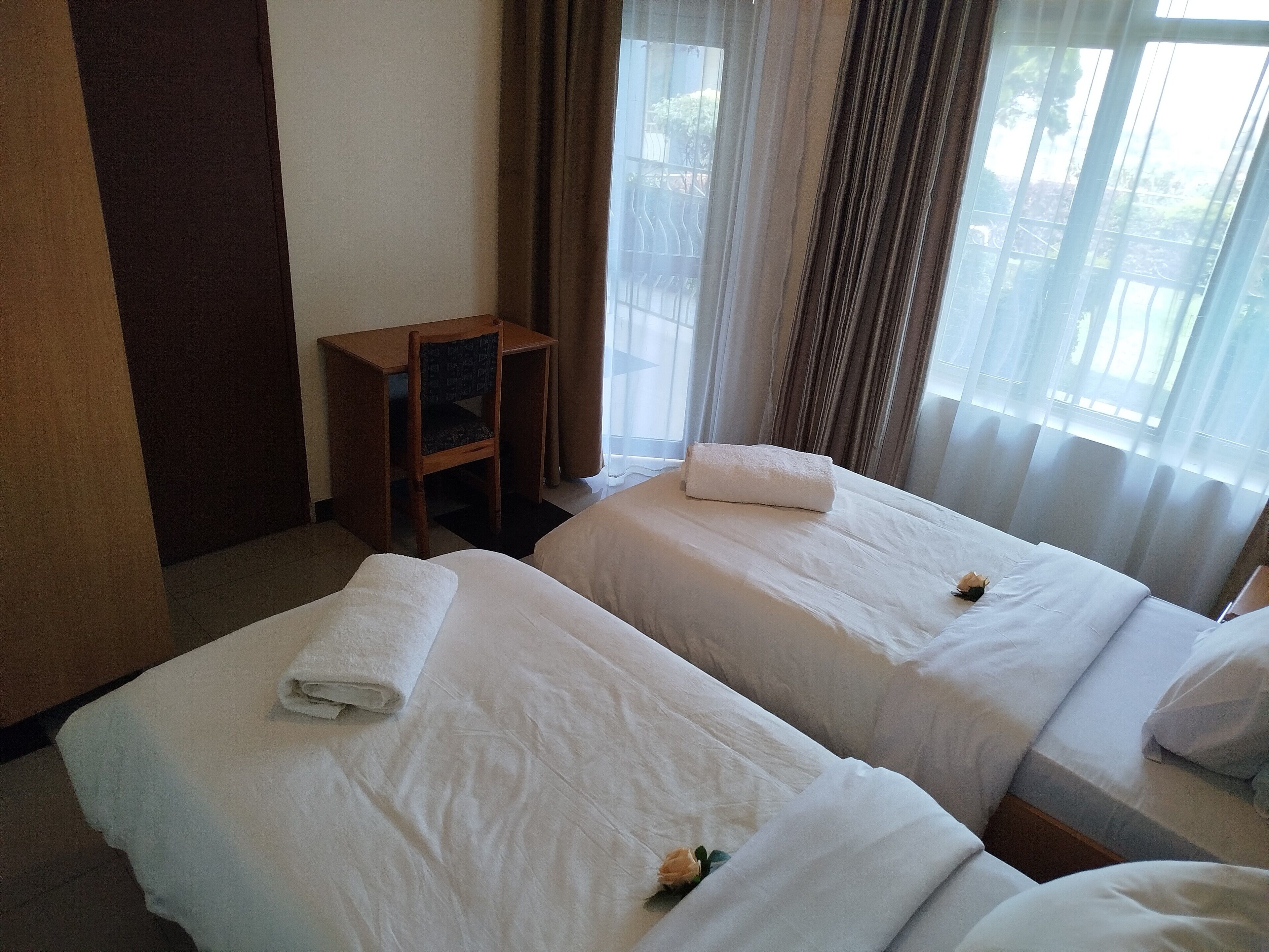 Une chambre d’hôtel avec deux lits, un bureau en bois et une chaise.