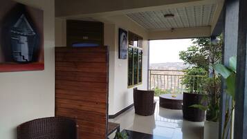 A balcony with wicker chairs, potted plants, and a view of the cityscape.