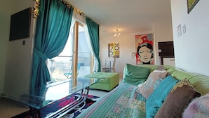 A room with a bed, a chair, a table, and a view of the city through a window. - 1 Bed Flat - Sleeps 5 - Pets - Garden - Parking (Manchester)