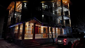 A multi-story building with a wooden facade, balconies, and a car parked in front. - Namgials by Sky Group (Manali)