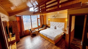 A wooden room with a bed, a desk, and a chair. There are large windows with curtains. - Namgials by Sky Group (Manali)