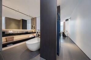 Een moderne badkamer met een grote spiegel, een vrijstaand bad en een wastafel met een zwart aanrecht.
