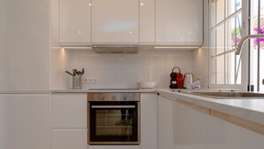 Een moderne keuken met witte kasten, een ingebouwde oven en een raam dat voor natuurlijk licht zorgt.