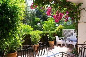 A patio area with potted plants, outdoor furniture, and a white lattice fence. - White Pearl Beach Elviria H1 (Marbella)