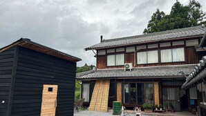 Perinteinen japanilainen rakennus, jossa on puinen ulkoverhous, tiilikatto ja sorapäällysteinen sisäpiha.