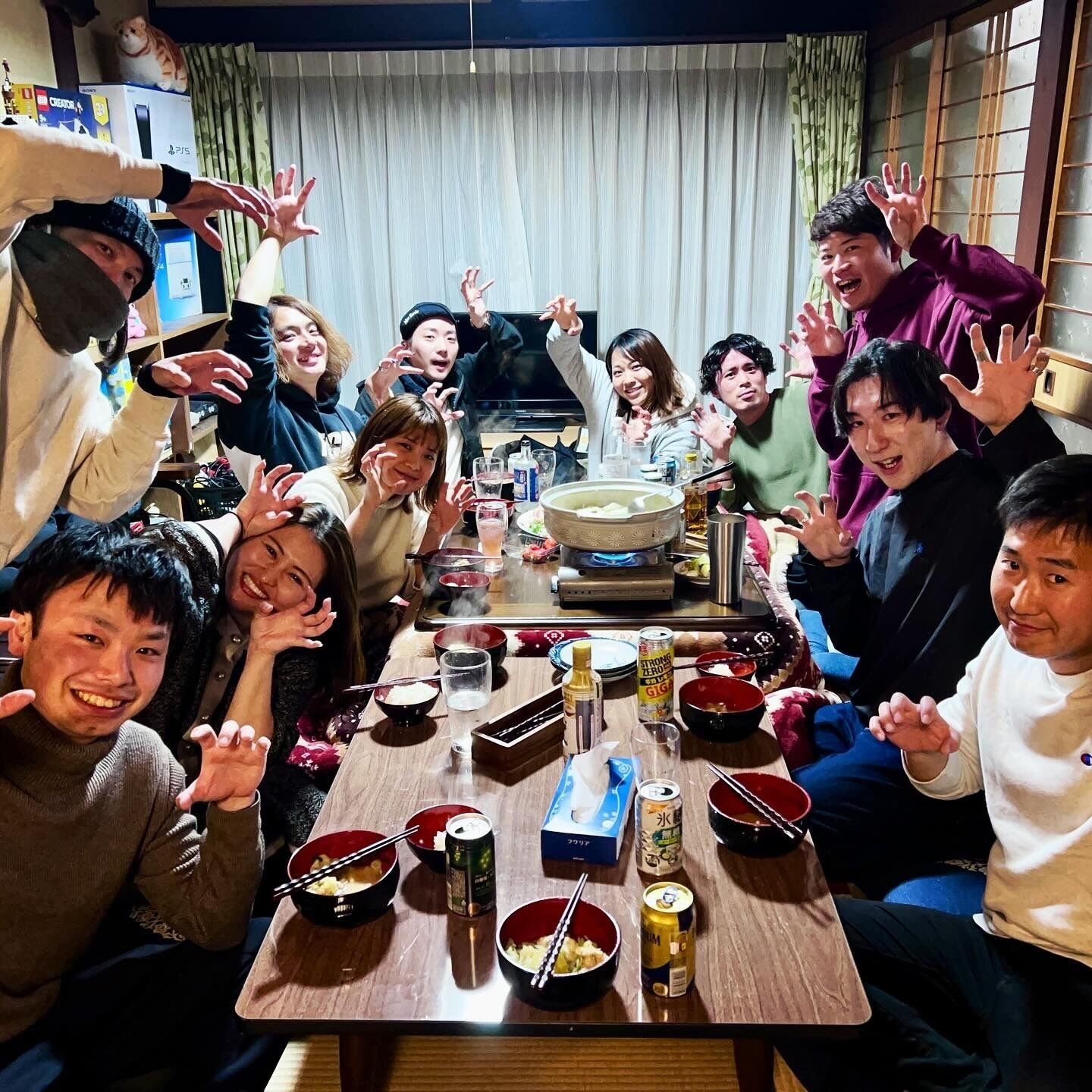 A group of people gathered around a table with various dishes and drinks, indicating a social or dining setting.