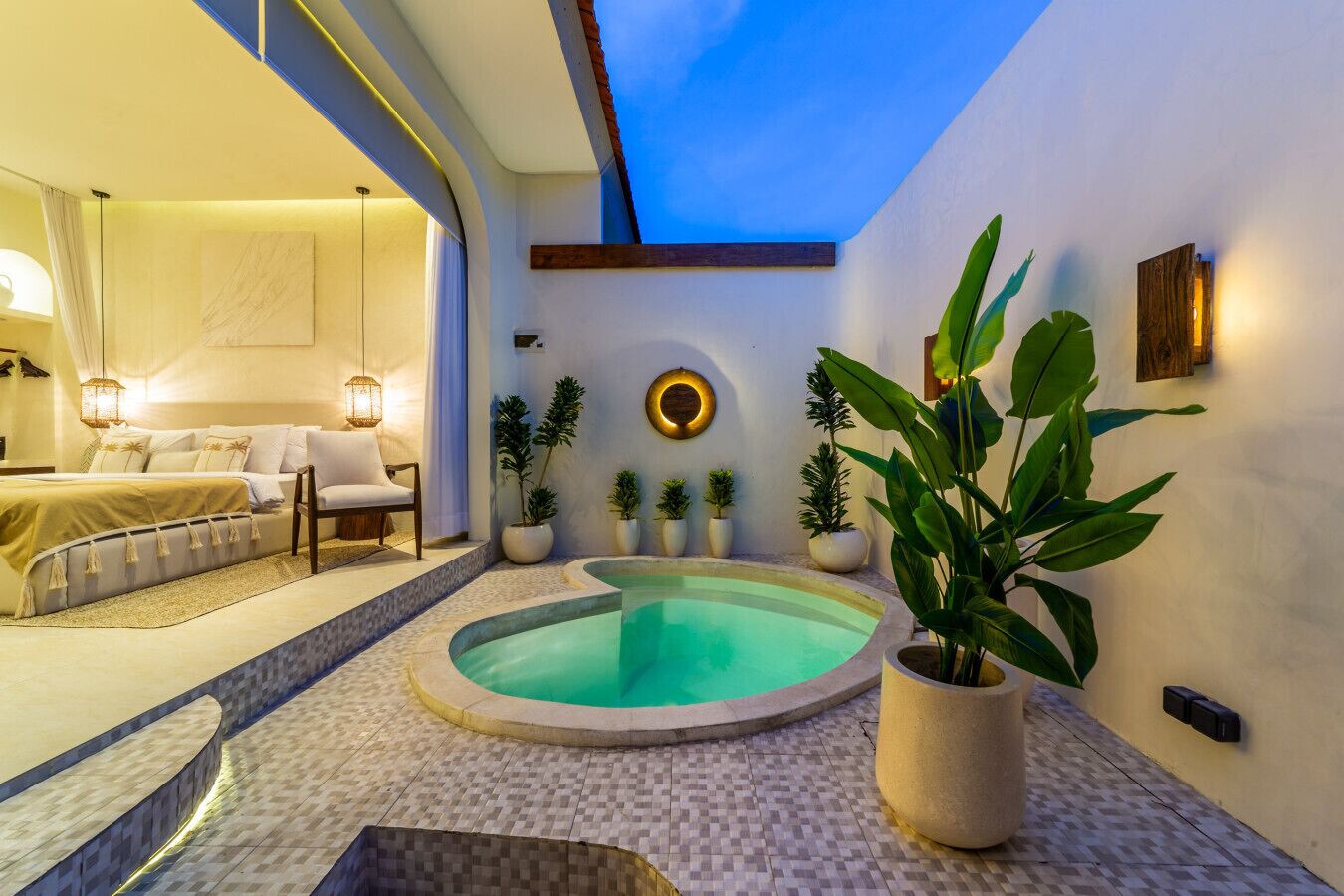 Une chambre moderne avec un grand lit, un petit coin salon et une piscine ronde.