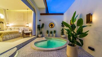 Une chambre moderne avec un grand lit, un petit coin salon et une piscine ronde.