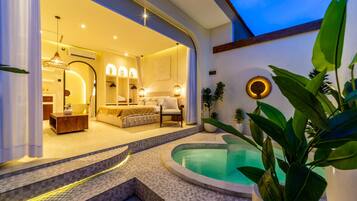 Un intérieur moderne doté d’un espace piscine, comprenant une chambre avec un lit et un coin salon, ainsi qu’un espace repas avec une table et des chaises.
