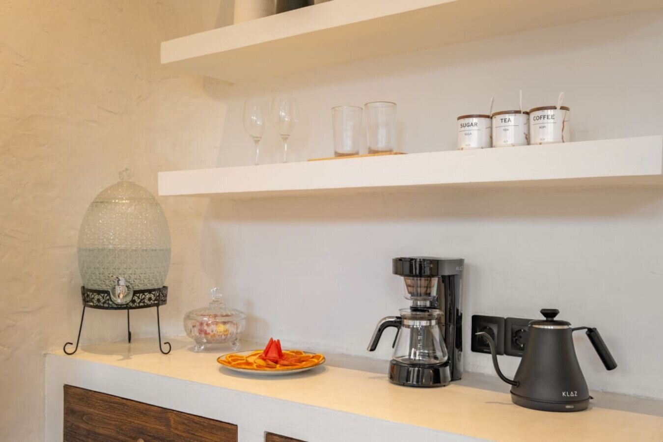 Un comptoir de cuisine avec une machine à café, du sucre, du thé et des récipients contenant du café.