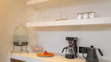 Un comptoir de cuisine avec une machine à café, du sucre, du thé et des récipients contenant du café.