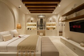 Ein modernes Schlafzimmer mit Bett, Sitzbank, Fernseher und integrierten Regalen.