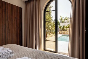 A bedroom with a large window, a bed, and a view of an outdoor swimming pool.