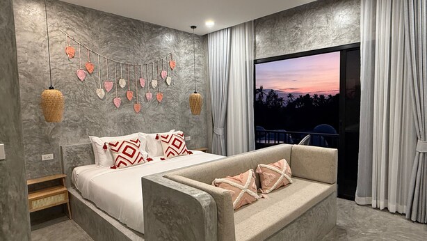 Une chambre moderne avec un lit, un canapé, un mur décoratif et une grande fenêtre avec des rideaux.