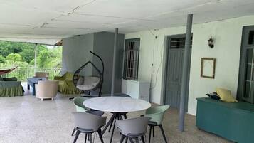 A covered outdoor seating area with a round table and chairs, a sofa, and a hammock.