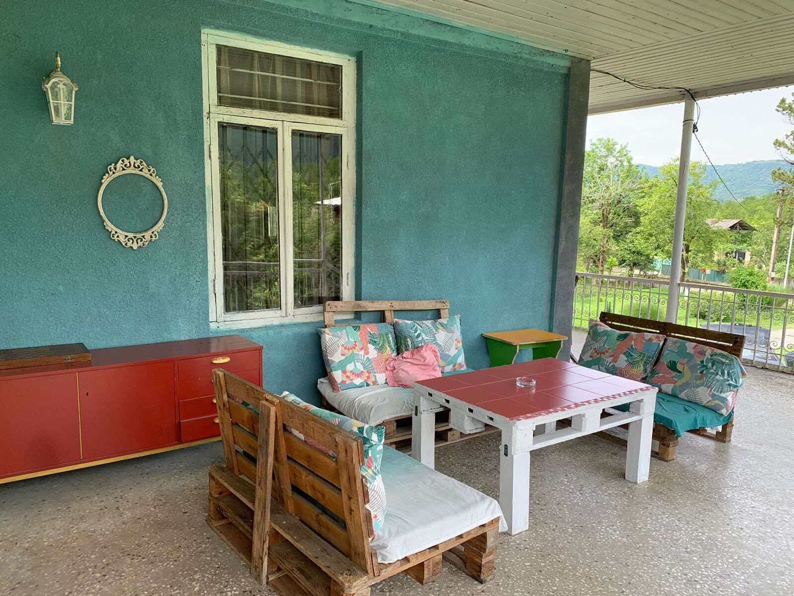 A cozy outdoor seating area with wooden furniture and a view of greenery.