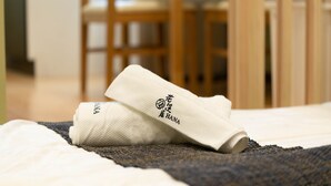 Siististi pedattu sänky, päällä valkoinen pyyhe ja toinen, taiteltu pyyhe, jossa on japaninkielisiä merkkejä.