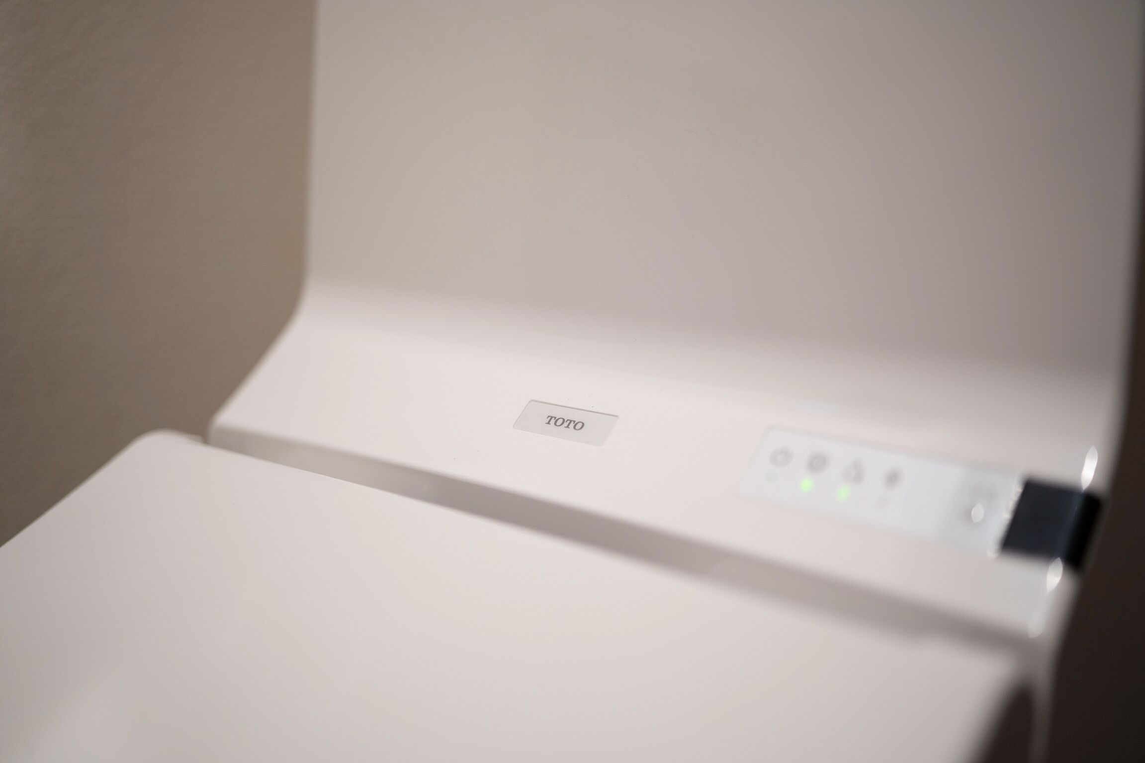 A white electronic device with a label "TOTO" and a control panel with buttons and indicator lights.