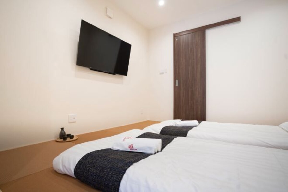 A hotel room with a bed, a television mounted on the wall, and a wooden door.