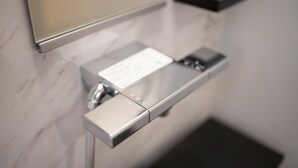 Moderni, metallinen käsiä kuivaava laite, joka on asennettu seinään ja jossa on ohjauspaneeli sekä paperinen käyttöohje.