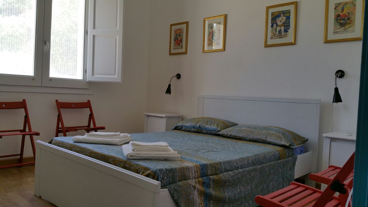Ein Schlafzimmer mit einem Bett, zwei Stühlen, einem Nachttisch und einem Fenster.