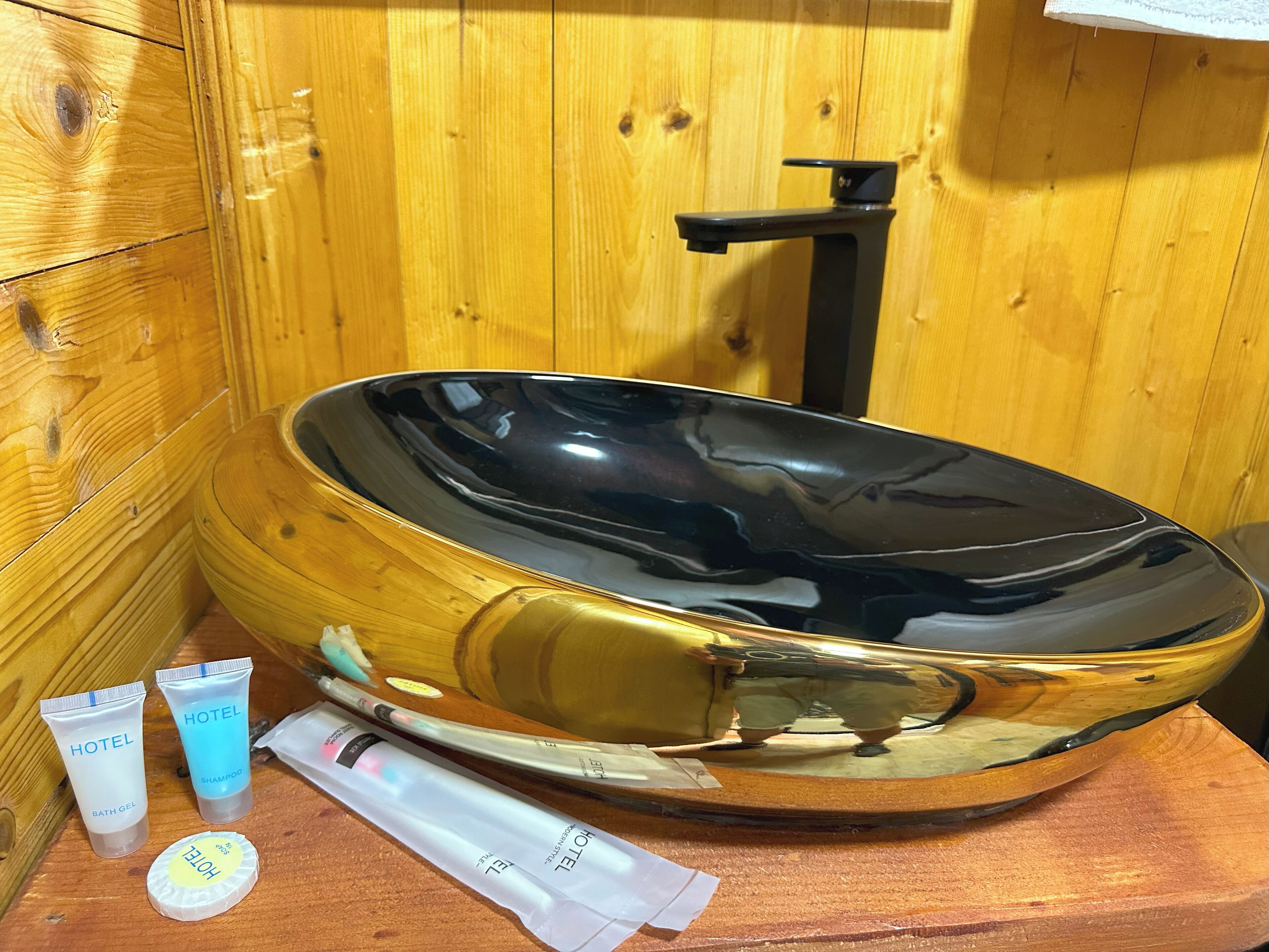 Une baignoire en bois, avec un intérieur noir, entourée de murs en bois.