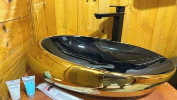 Una bañera de madera con interior negro, rodeada de paredes de madera.