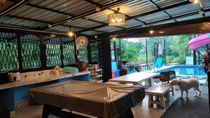 Un restaurante con piscina, mesas y un perro.