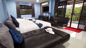 Habitación de hotel con dos camas, un sofá, un balcón con vistas y una zona de comedor.