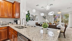 A modern kitchen with granite countertops, stainless steel appliances, wooden cabinets, and pendant lighting. - 5014 Tideview Circle #9 (Orlando)