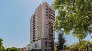 Ein hohes, mehrstöckiges Gebäude mit modernem architektonischen Design, das auf jeder Etage Balkone bietet.