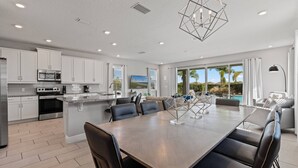 A modern kitchen with white cabinets, stainless steel appliances, and a large island with seating.