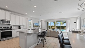 A modern kitchen with white cabinets, a granite island, and a large island bar.
