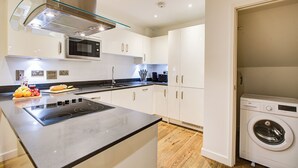 A modern kitchen with a built-in microwave, stainless steel range hood, and a large island with a stovetop.
