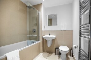 A modern bathroom with a glass shower enclosure, a pedestal sink, a toilet, and a towel rack.
