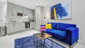 A modern living room with a blue sofa, a coffee table, and a kitchen in the background.