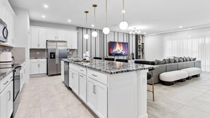 A modern kitchen with white cabinetry, stainless steel appliances, and a central island.