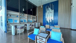 A modern library with wooden furniture, blue cushions, and a large wall of framed pictures. - Baan Kiang Fah Hua Hin By Thita (Hua Hin)