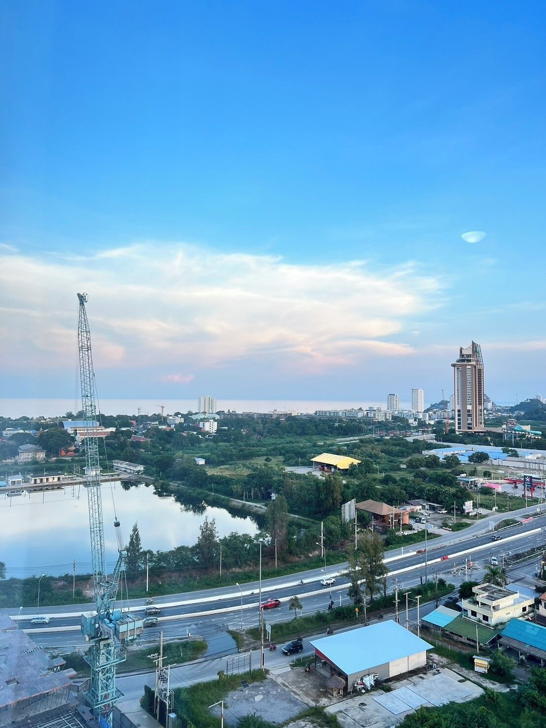 A cityscape with a prominent communication tower, a body of water, and a mix of residential and commercial buildings.