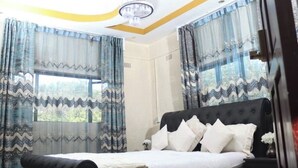 Ein Schlafzimmer mit einem großen Bett, durchsichtigen Vorhängen und einer Deckenleuchte.