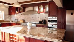 Eine Küche mit Granit Arbeitsplatten, Edelstahlgeräten und Holzschränken.