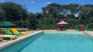 Une piscine rectangulaire à l’eau d’un bleu cristallin, entourée de chaises longues et de parasols.