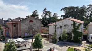 A courtyard with a stone building, outdoor seating, and trees. - Duplex in charming neighborhood overlooking chateau, close to downtown and all amenities (Clisson)